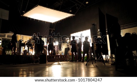 Behind the scenes of video shooting production crew team silhouette and camera equipment in studio.