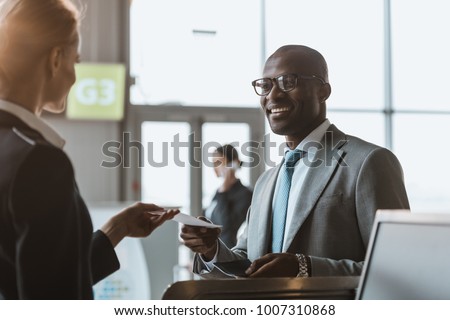 happy young businessman giving passport and ticket to staff at airport check in counter