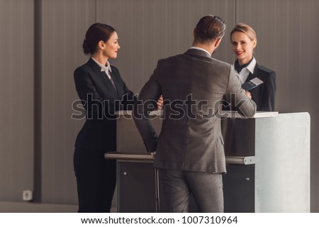 rear view of young businessman standing at airport check in counter
