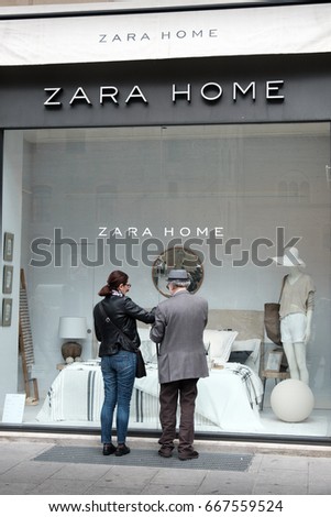 Bologna, Italy, 1 May 2017 - an old man and a woman look at the showcase of the Zara Home furnishing store in Bologna