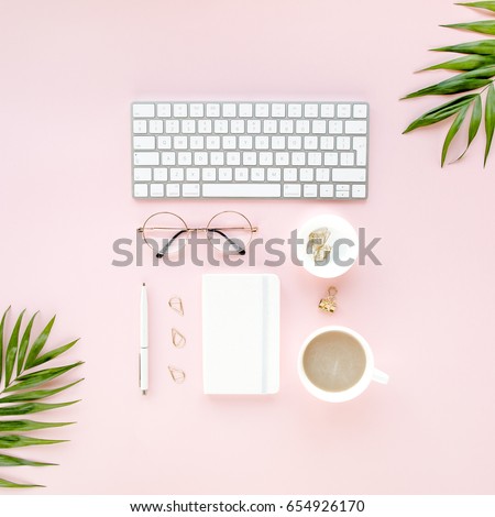 Office table desk with computer, green leaves palm, clipboard. Magazines, social media. Top view. Flat lay. Home office workspace. Women's fashion accessories isolated on pink background.