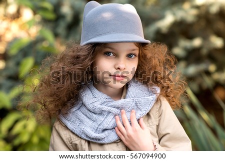 Portrait of little cute smiling girl in funny cat hat with long curly hair. Outdoor in the garden.
