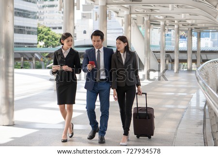 Group of business people checking flight from mobile phone during walk to check in at airport. Boss sending staff / employee to business trip conference.