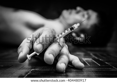 syringe in overdose asian male drug addict hand, BW photo