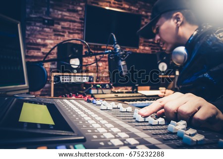 music producer working on sound mixer in recording studio or DJ working in broadcasting studio