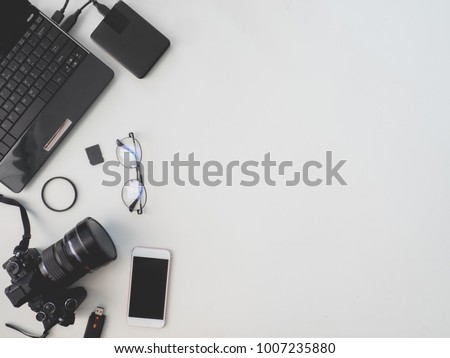 top view of photographer concept with digital camera, memory card, external harddisk and camera accessory on white background with copy space.
