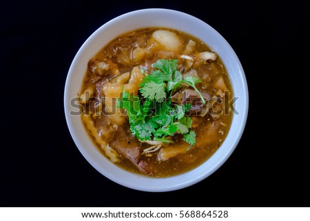 Braised Fish Maw in Red Gravy put the bowl in white against a black background. Sprinkle with parsley on top.