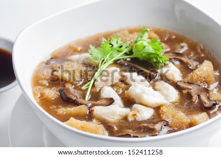 Braised Fish Maw in Red Gravy with crab in bowl on white background.