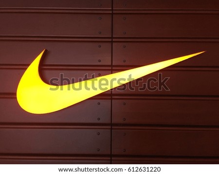 HONG KONG on 31ST MARCH 2017. Yellow Nike logo over brown background. Nike, Inc. is an American multinational corporation that designs, develops, manufactures and sells footwear and other items
