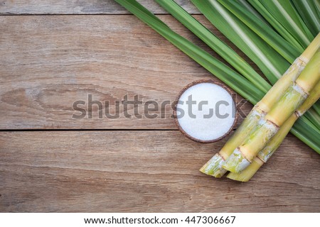 Top view white sugar and sugar cane and leaf on wooden background