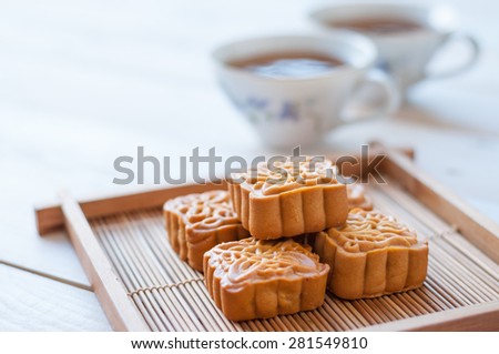 Retro vintage style Chinese mid autumn festival foods. Traditional mooncakes on table setting with teacup.