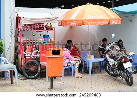 Can Tho, Vietnam. June 14, 2014 : Unidentified customers having a break at streets stall with Coca Cola push cart and umbrella at Can Tho, Vietnam on June 14, 2014.