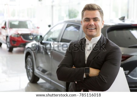 Portrait of a professional car salesman posing confidently at the dealership salon new cars on the background copyspace positivity friendly assistant worker manager retailer seller sales occupation.