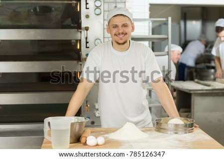 Portrait of a handsome young male baker smiling to the camera posing at his kitchen while working bakery shop store cook chef profession occupation career positivity food nutrition organic qualified