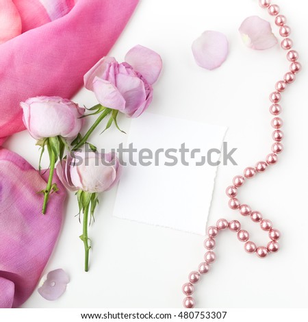 pink roses and pearl necklace on white background. Top view.