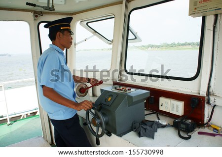 DONG THAP, VIET NAM- JANUARY 27. On cabin of ferry boat, ferryman wear uniform control the wheel to transportation passenger cross the river at Dong Thap, Vietnam, January 27, 2013.