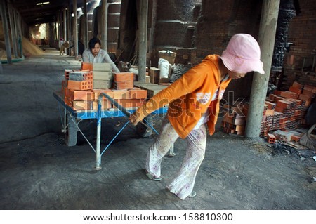 VINH LONG, VIET NAM- JULY 1: Worker working at brick factory, workwoman in hard work, pulling up the rickshaw with full of brick in Vinh Long, Viet Nam on July 1, 2013