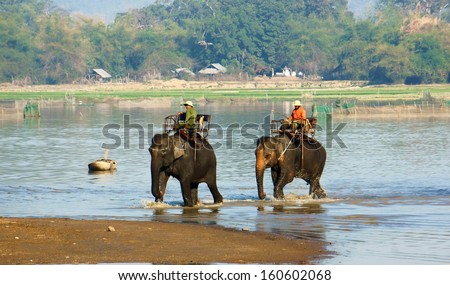 BUON ME THUOT, VIET NAM, FEBRUARY 18: Mahout riding elephant across the lake in Buon Me Thuot, Viet Nam on February 18, 2013