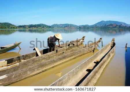 BUON ME THUOT, VIET NAM- FEBRUARY 18: People clean dug out canoe (boat) to transport for travel in Buon Me Thuot, Viet Nam on February 18, 2013