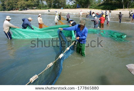 BINH THUAN, VIETNAM- JAN 22: Team work of fisherman on beach, group of people pull fishing net to catch fish, stand in row, person move to seashore, crowded atmosphere, fresh air,Viet Nam, Jan22, 2014