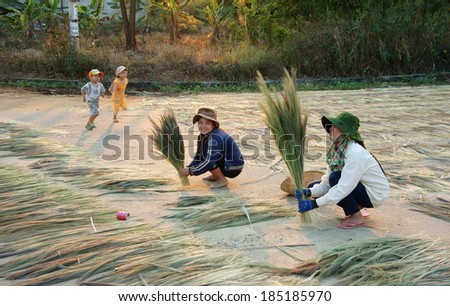 BUON ME THUOT, VIETNAM- FEB 6: Vietnamese young labor dry leaf on country road, atmosphere of Vietnam countryside at evening, woman working, unidentified children play together, Viet Nam, Feb 6, 2014