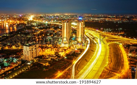 Amazing nightscape of Ho chi Minh city, Vietnam from high view, city bright in yellow electric light, trail on road, landscape of new urban in radiant colors at night
