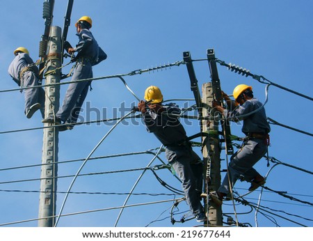 DONG THAP, VIET NAM- SEPT 23: Group Asian electrician climb high in pole to work, lineman with cable network, man repair electric post with belt safety, is industry service, Vietnam, Sept 23, 2014
