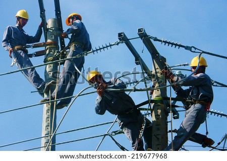 DONG THAP, VIET NAM- SEPT 23: Group Asian electrician climb high in pole to work, lineman with cable network, man repair electric post with belt safety, is industry service, Vietnam, Sept 23, 2014