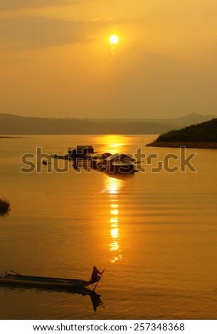 Abstract Vietnamese rural at sunset, sun on yellow sky, vibrant color, silhouette of people rowing a row boat on Nam Ka Lake, Dakak, Vietnam, house on water, make amazing landscape of Viet Nam travel
