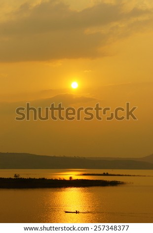 Abstract Vietnamese rural at sunset, sun on yellow sky, vibrant color, silhouette of people rowing a row boat on Nam Ka Lake, Dakak, Vietnam, house on water, make amazing landscape of Viet Nam travel
