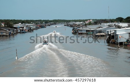 Lively scene on waterway at Mekong Delta, Vietnam. Motor boat move in fast on Ca Mau river, motorboat make wave on water, riverside residential with house make from metal sheet at Camau, Vietnam