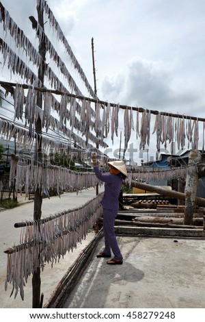 CAMAU, VIET NAM- JULY 16, 2016: Vietnamese woman dry seafood at Ca Mau fishing village, Mekong Delta. Dried fish is popular Vietnam food, can store for long time