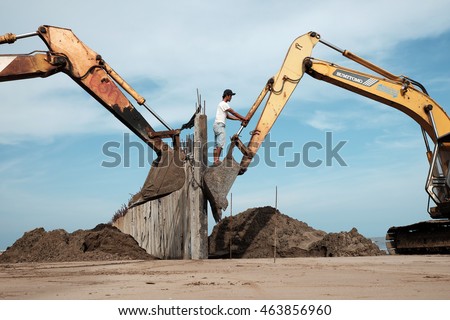 CA MAU, VIET NAM- JULY 16,2016: Vietnamese excavator driver control vehicle to build breakwater at beach to protect seaside from erosion at Camau, Vietnam