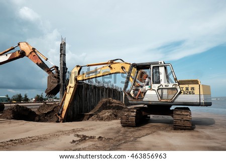 CA MAU, VIET NAM- JULY 16,2016: Vietnamese excavator driver control vehicle to build breakwater at beach to protect seaside from erosion at Camau, Vietnam