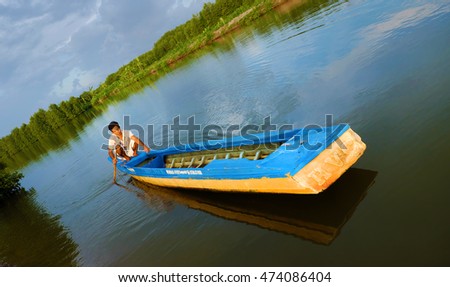 CA MAU, VIET NAM- JULY 16, 2016: Vietnamese man catch fish on river, people and row boat reflect on water, beautiful green tree from mangrove forest make wonderful scene in evening at Mekong Delta