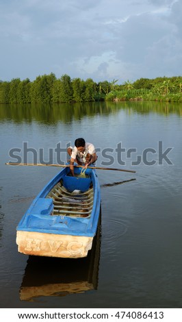 CA MAU, VIET NAM- JULY 16, 2016: Vietnamese man catch fish on river, people and row boat reflect on water, beautiful green tree from mangrove forest make wonderful scene in evening at Mekong Delta