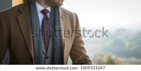 Man in tailored trench coat and suit posing outdoors