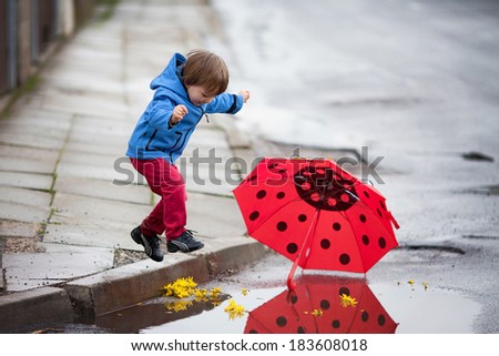Little boy, jumping in muddy puddles