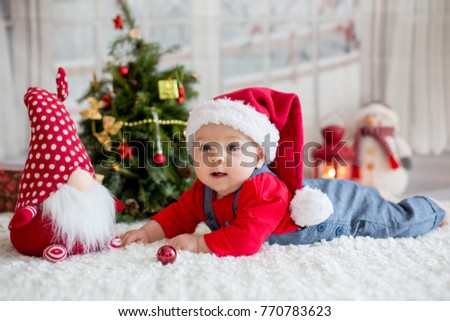 Portrait of newborn baby in santa clothes and christmas hat lying on the ground Portrait of newborn baby in santa clothes and christmas hat lying on the ground
