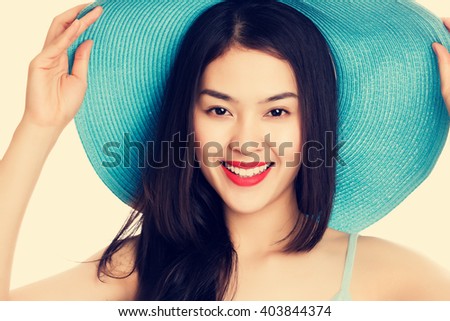 Young Asian woman wearing blue straw hat with expression of surprise, vintage tone style.