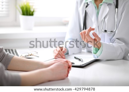Close up of doctor and patient sitting at the desk near the window in hospital