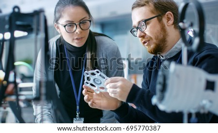 Young Talented Male and Female Engineers In a Modern Laboratory Discussing Prototype built with the Help of 3D Printer.