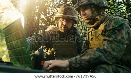 Military Staging Base, Officer Gives Orders to Chief Engineer, They Use Radio and Army Grade Laptop. They're in Camouflaged Tent in a Forest. They're on Reconnaissance Operation/ Mission.