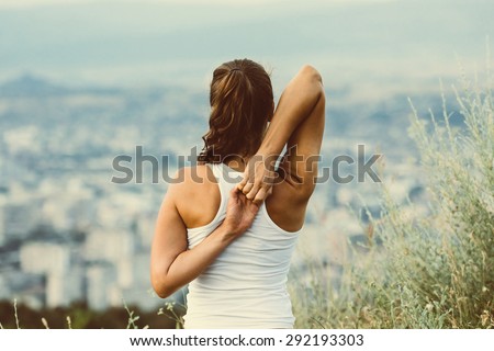 Young woman sits in yoga pose with city on background. Freedom concept. Calmness and relax, woman happiness. Toned image