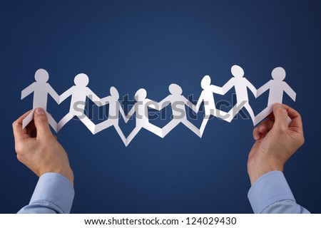 Teamwork concept with paper chain group of people holding hands held over blue background