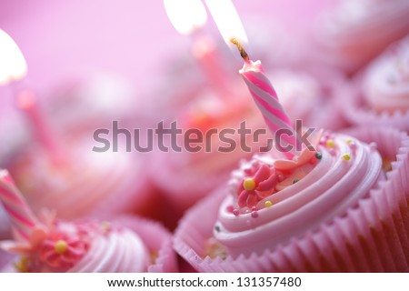 Birthday pink cupcakes with burning candles - stock photo