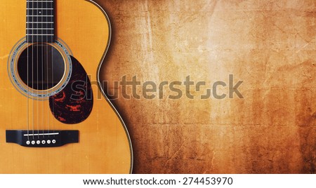Acoustic guitar resting against a blank grunge background with copy space