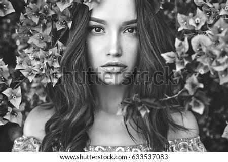 Black and white outdoor fashion photo of beautiful young woman surrounded by flowers spring blossom Black and white outdoor fashion photo of beautiful young woman surrounded by flowers spring blossom