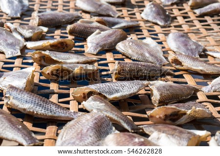 small salted fish drying under the sun in a basket