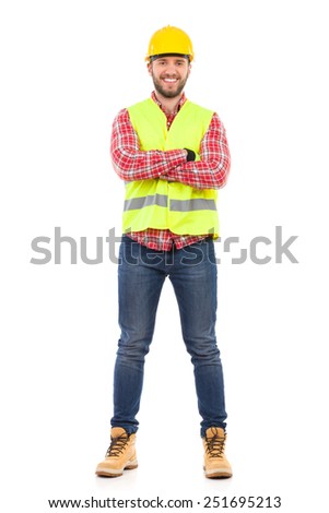 Smiling construction worker in yellow helmet and lime waistcoat posing with arms crossed. Full length studio shot isolated on white.